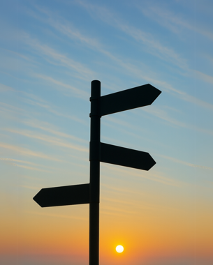 A photo of a signpost against a sunrise background