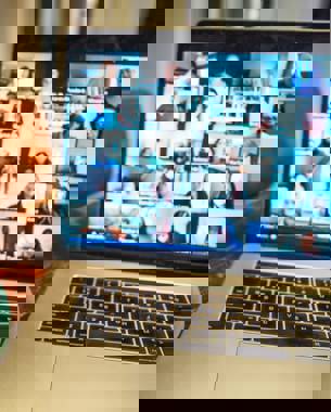 Pictured is a laptop screen showing an online meeting with many in attendance.