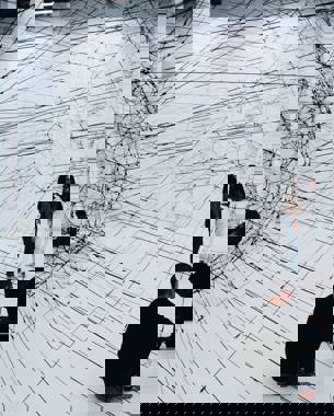 Photo of an artwork consisting of two translucent black spheres made from ropes. They are connected to each other like a kind of network. Further in the photo you can see that there are still people working on it.